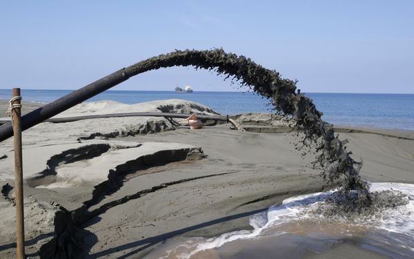 A pipe spews water mixed with waste black sand coming from a magnetized black sand mining equipment along the shore line of Ilocos Sur, in northern Philippines