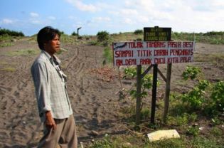 Sumanto, secretary of the Kulonprogo Coastal Farmers Association (PPLP), walking past a sign in Bugel village that reads: ‘Reject the iron sand mine to the last drop of blood. For our grand children's sake.'